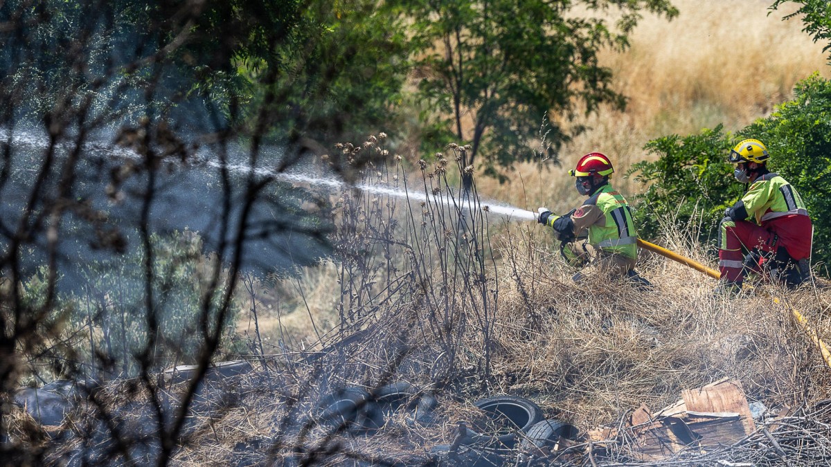 TOLEDO, 26/06/2025.- Efectivos del cuerpo de bomberos trabajan en la extinción del incendio declarado este jueves en una parcela en la que se acumulaba basura en el asentamiento del Cerro de los Palos, en Toledo, donde las fuerzas de seguridad están procediendo a desalojar a las familias. EFE/ Ismael Herrero